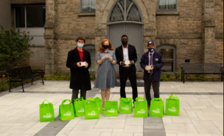 group of people standing with green bags