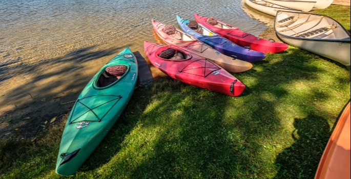 Different coloured canoes in front of lake