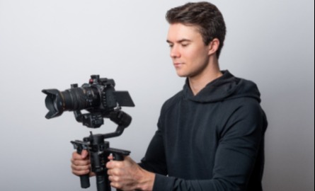 Man holding a large camera on white background
