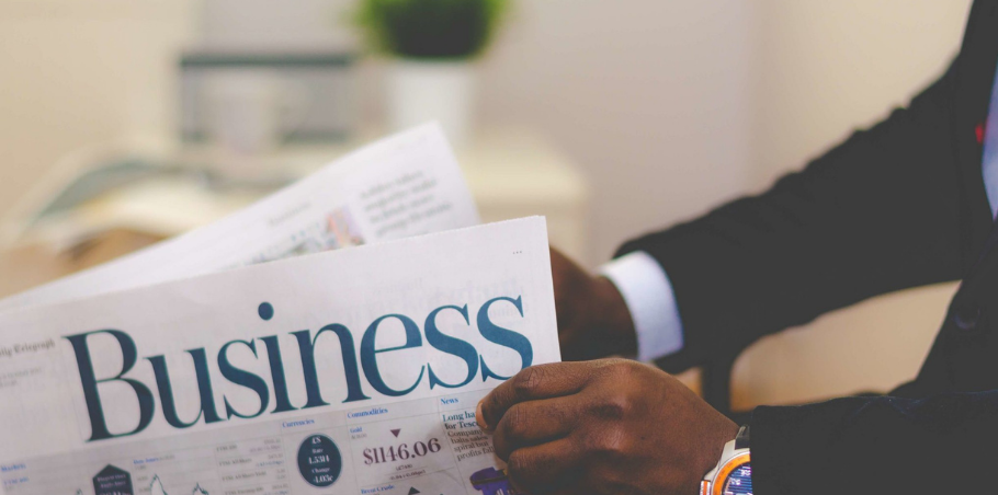 Person holding a newspaper with "business" as headline