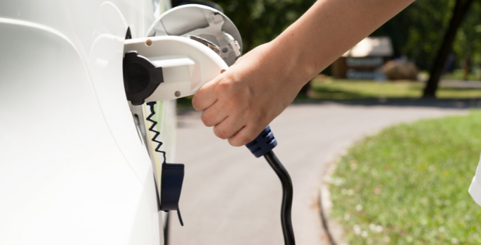 persons hand charging an electric vehicle