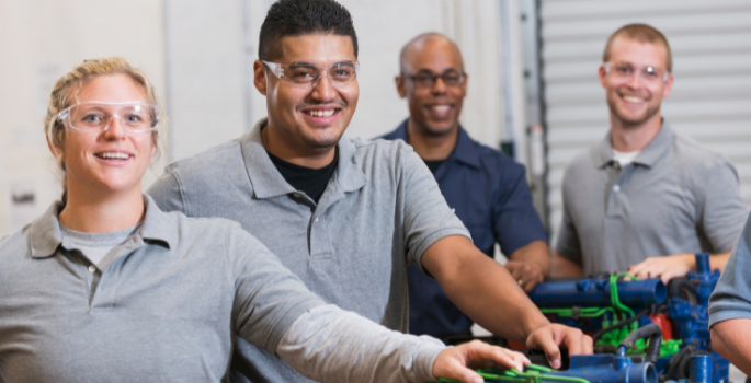 4 workers posing with mechanical device