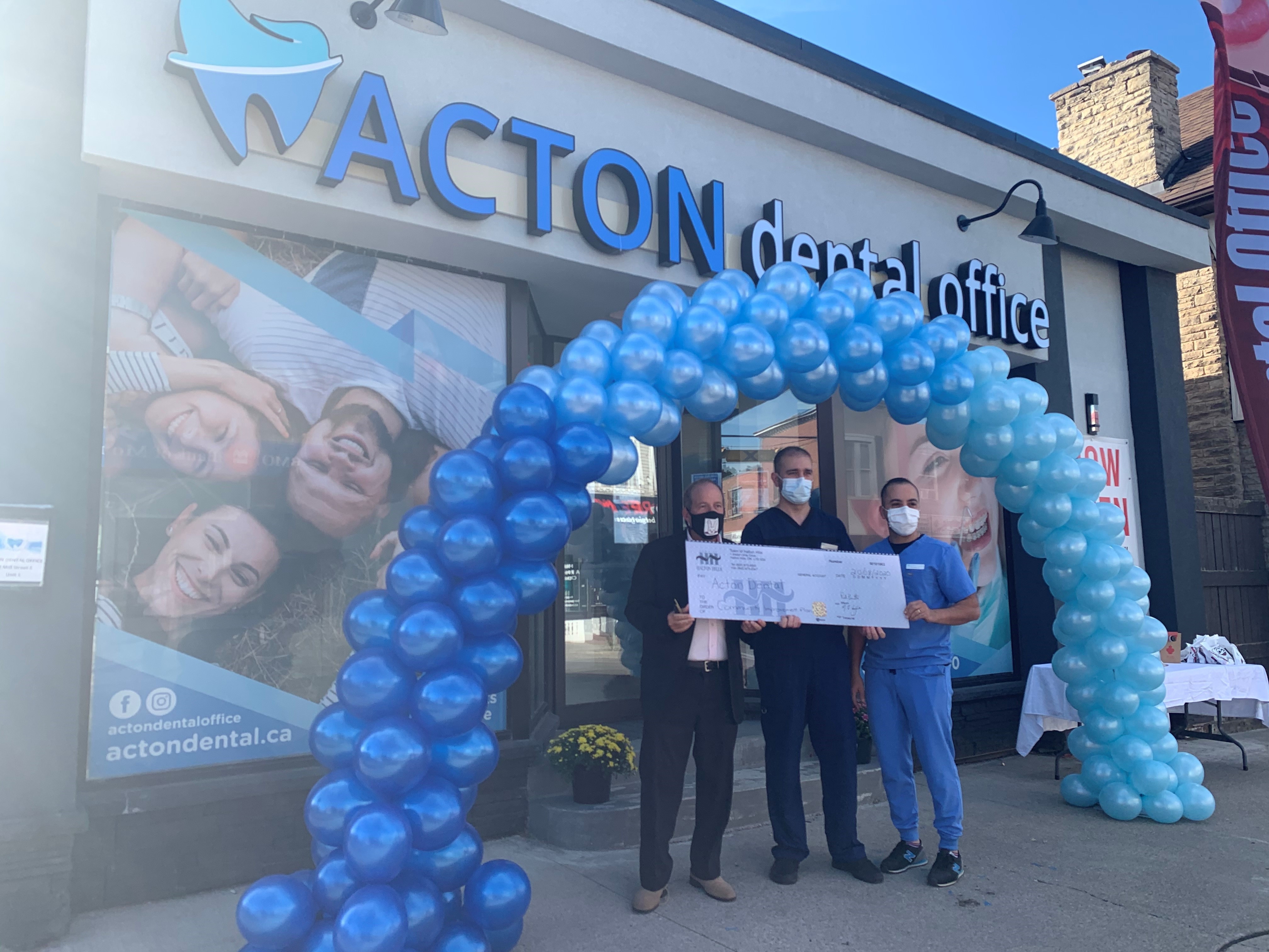 group of people in front of a storefront holding a big cheque