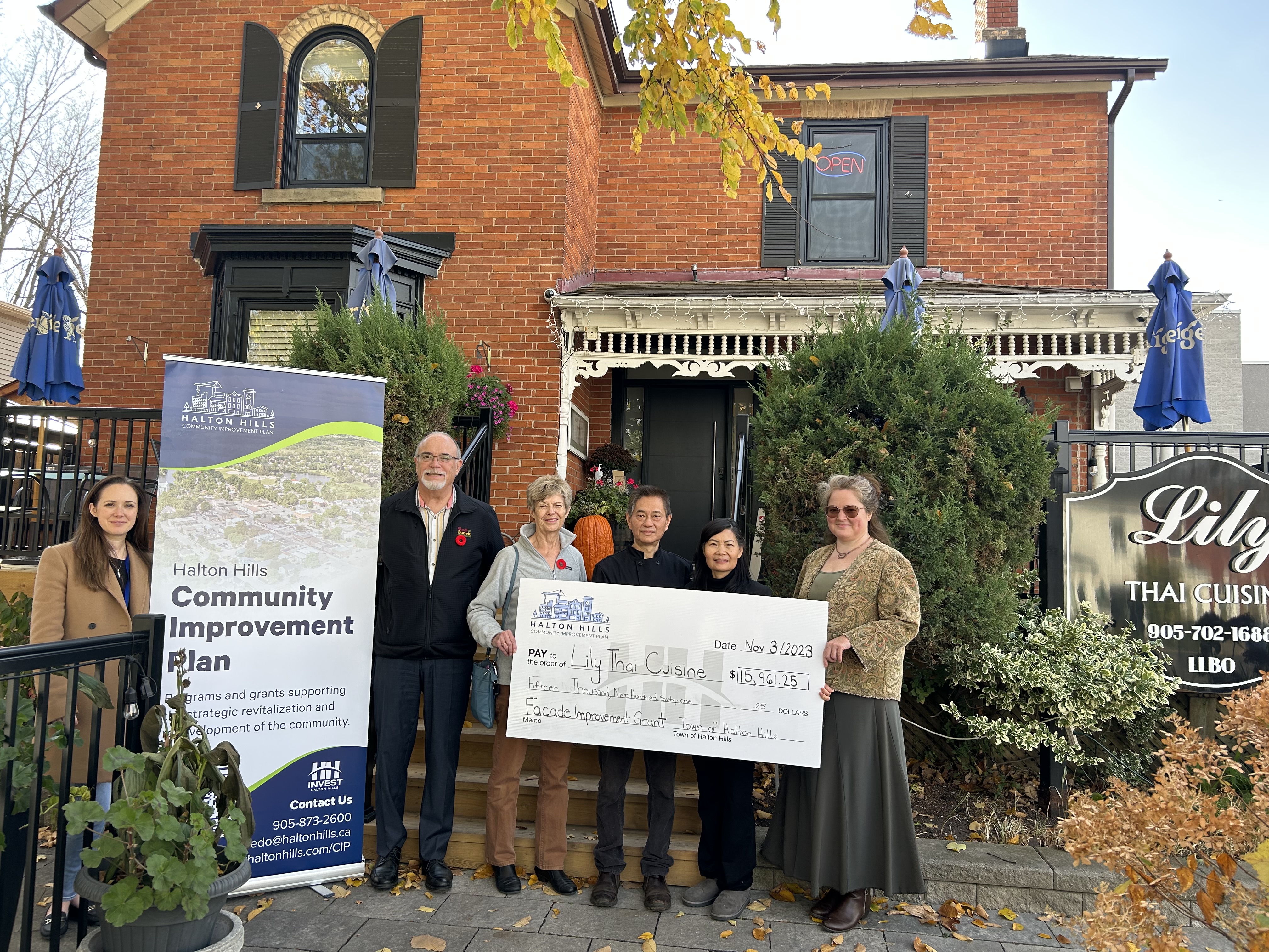 People presenting large cheque in front of restaurant 